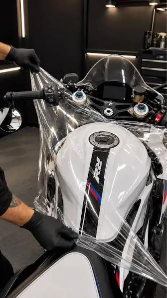 Instalador aplicando PPF transparente no tanque de uma moto esportiva